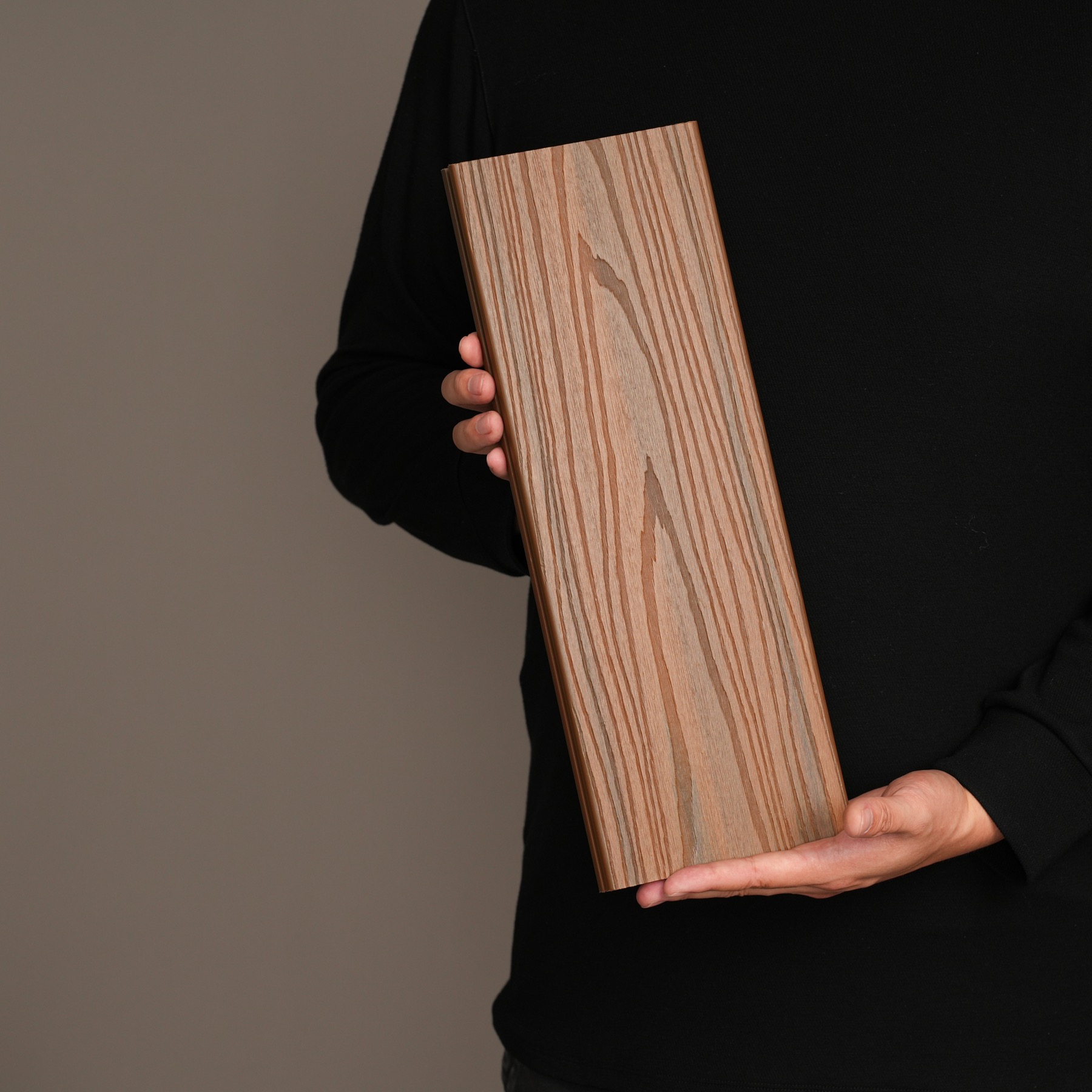 AN JU JIE WPC decking sample held against a dark studio background